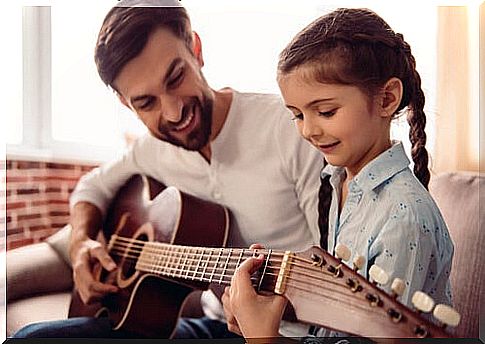 Father teaching his daughter to play the guitar