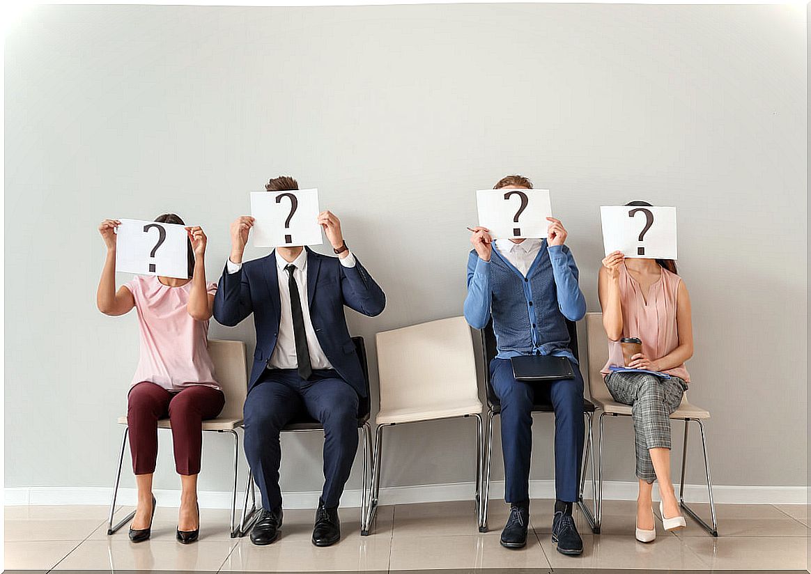 People holding a sign with a question mark on the face