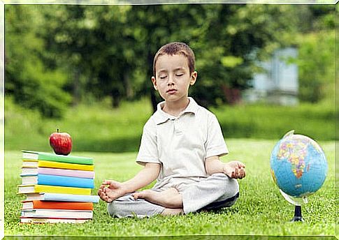 Boy practicing meditation with school books beside