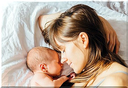 Mother cuddling her baby in bed