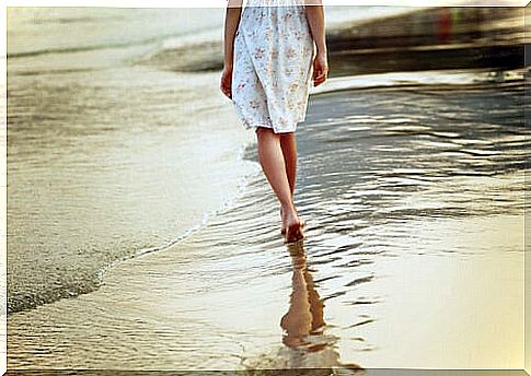 Woman walking on the sand on the beach barefoot